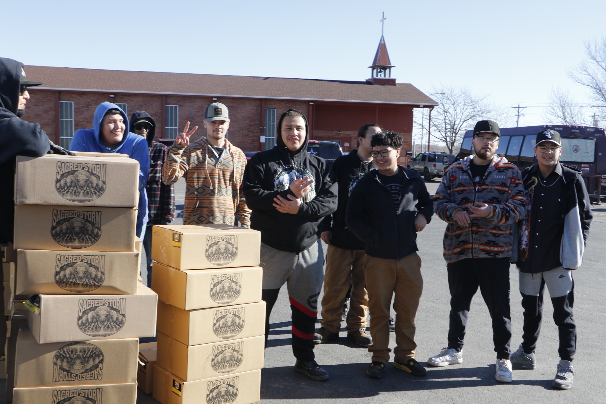 Young Native workforce participants with boxes of Sacred Storm Buffalo products during a community food distribution